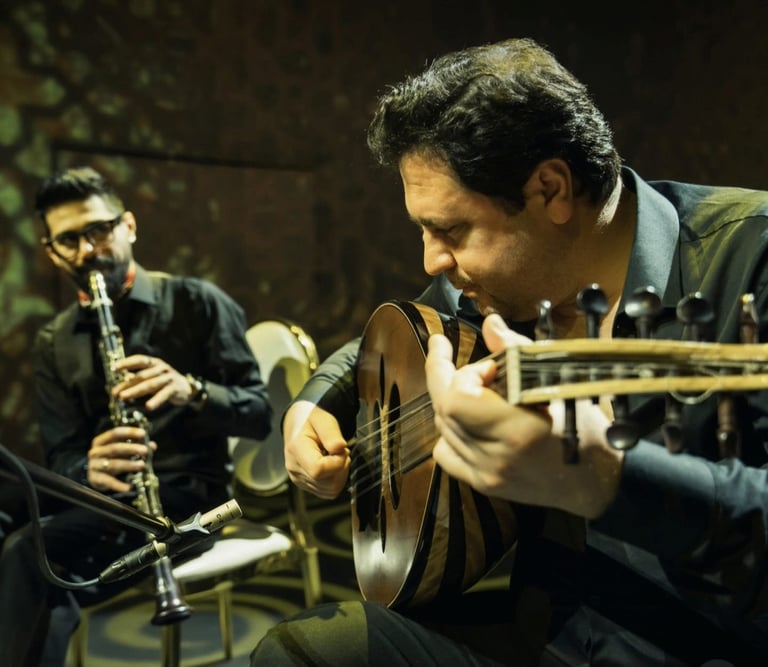 Two musicians performing in a jazz ensemble; one playing acoustic guitar in foreground, another playing saxophone in background